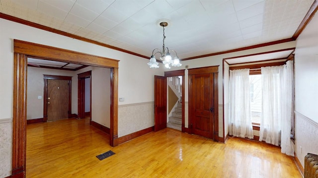 unfurnished dining area featuring crown molding, an inviting chandelier, and light hardwood / wood-style flooring