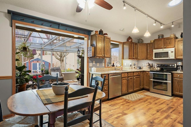 kitchen featuring pendant lighting, sink, ceiling fan, light hardwood / wood-style floors, and stainless steel appliances