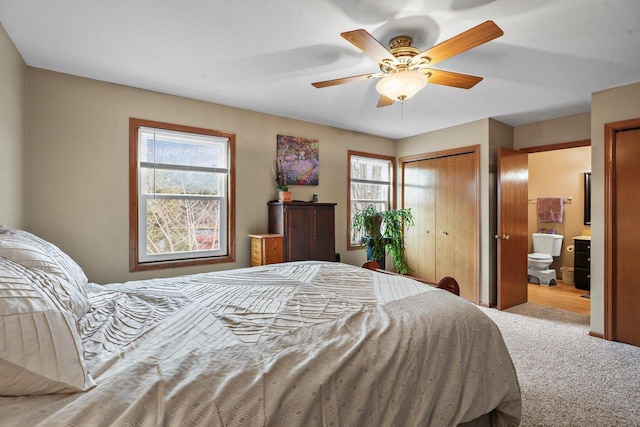 carpeted bedroom with ensuite bath and ceiling fan