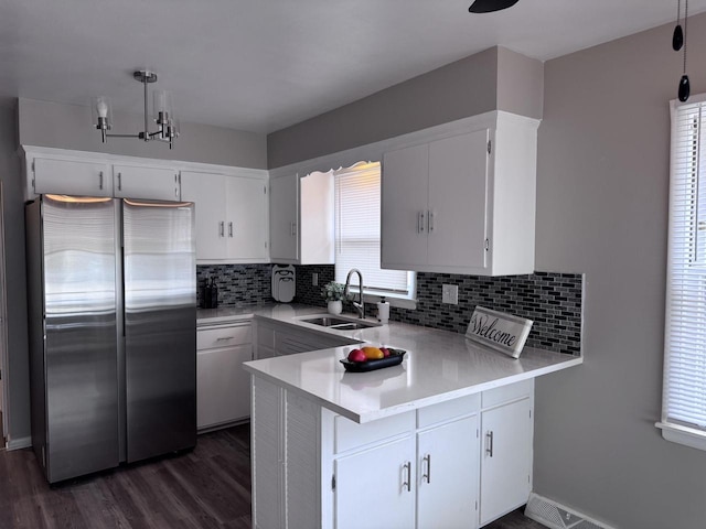 kitchen with white cabinetry, stainless steel fridge, kitchen peninsula, and sink