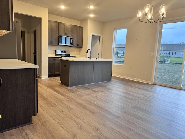 4414 20th St, Kenosha, WI 53144 - kitchen with stainless steel appliances, dark brown cabinetry, light countertops, a chandelier, and light wood-type flooring