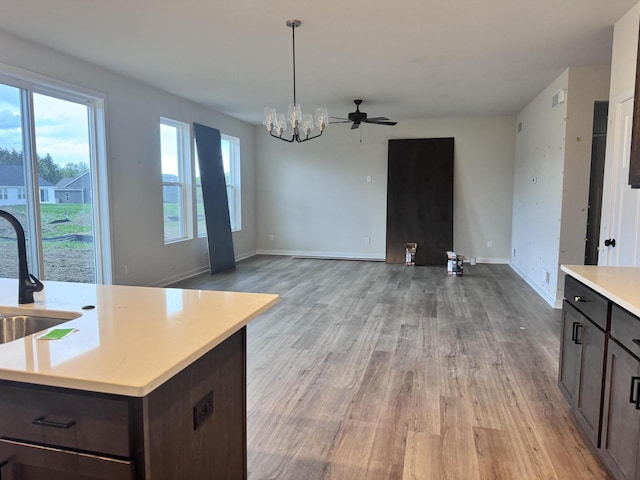 4414 20th St, Kenosha, WI 53144 - kitchen featuring light wood-type flooring, light countertops, a chandelier, dark brown cabinetry, and a sink