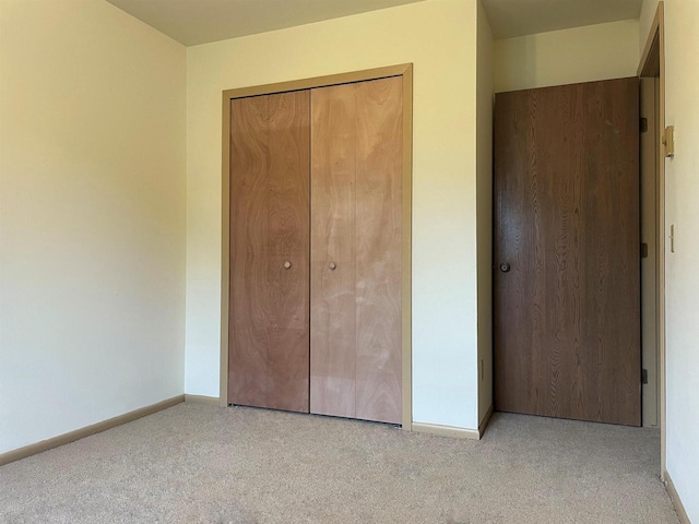 unfurnished bedroom with light colored carpet and a closet