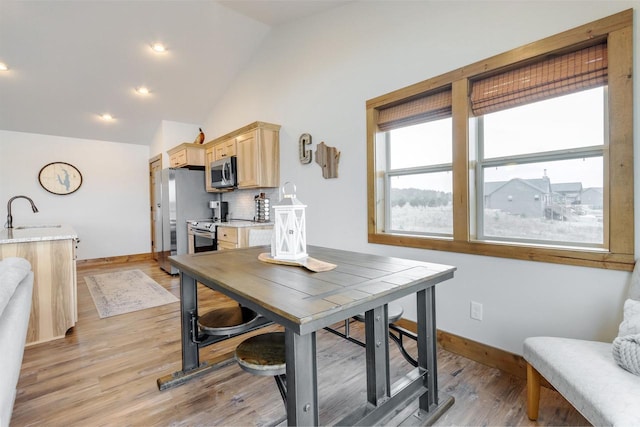 dining area featuring sink, high vaulted ceiling, and light wood-type flooring