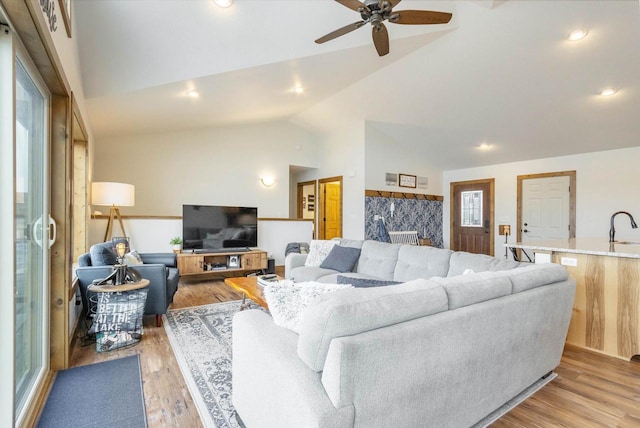 living room featuring lofted ceiling, sink, ceiling fan, and light hardwood / wood-style flooring