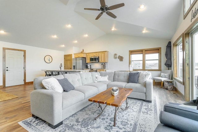 living room featuring high vaulted ceiling, light hardwood / wood-style floors, sink, and ceiling fan