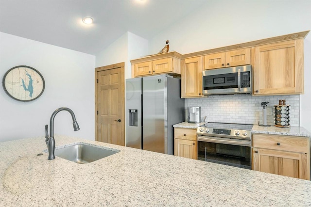 kitchen featuring appliances with stainless steel finishes, lofted ceiling, sink, backsplash, and light stone counters