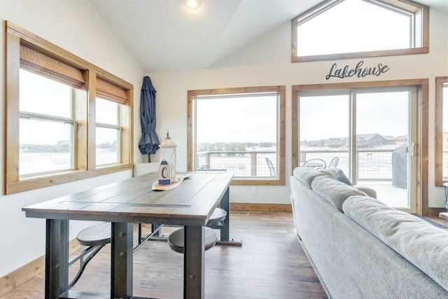 dining area with vaulted ceiling, wood-type flooring, and a water view