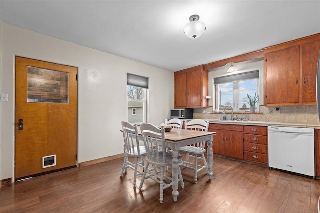 kitchen with white dishwasher, sink, wood-type flooring, and tasteful backsplash