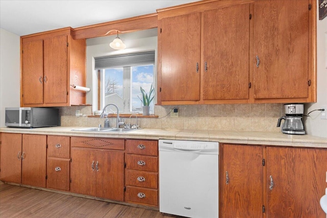 kitchen with light hardwood / wood-style floors, dishwasher, sink, and decorative backsplash