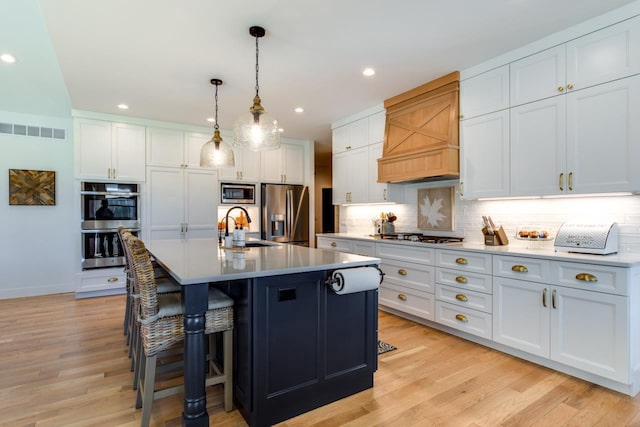 kitchen featuring stainless steel appliances, white cabinetry, sink, and an island with sink