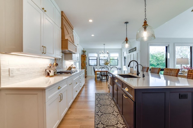 kitchen with white cabinetry, a large island, sink, and decorative light fixtures