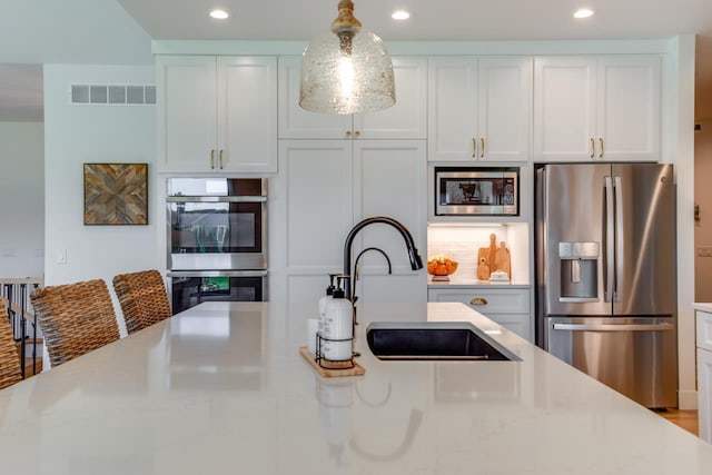 kitchen featuring white cabinetry, appliances with stainless steel finishes, light stone countertops, and sink