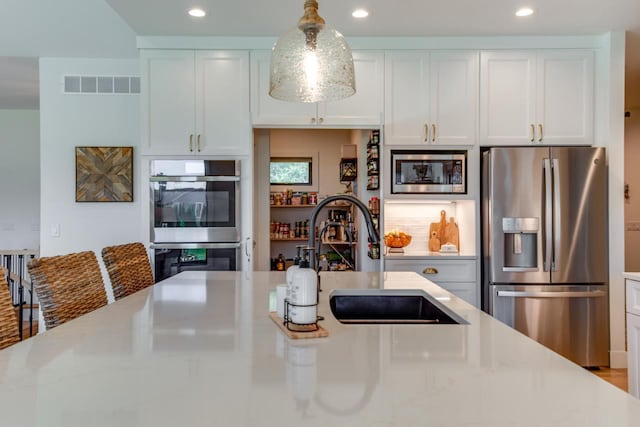 kitchen featuring sink, light stone countertops, white cabinets, and appliances with stainless steel finishes