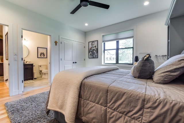 bedroom with connected bathroom, light hardwood / wood-style floors, a closet, and ceiling fan