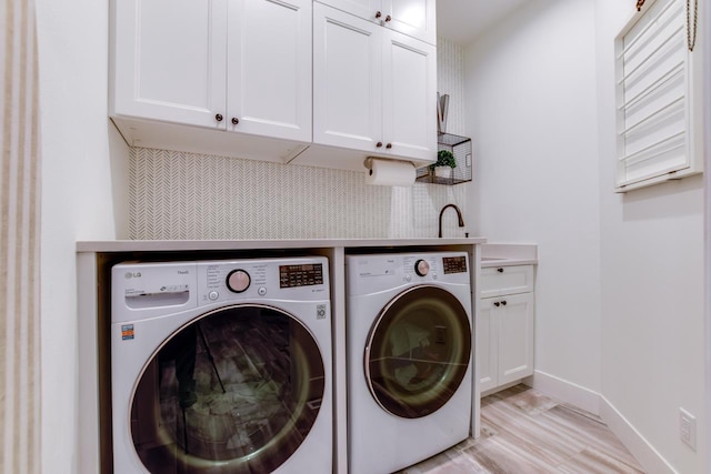 clothes washing area featuring cabinets, independent washer and dryer, and light hardwood / wood-style floors