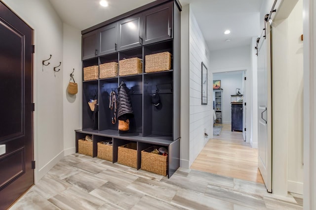 mudroom with a barn door and light wood-type flooring