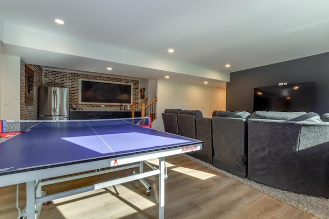 playroom featuring wood-type flooring and brick wall