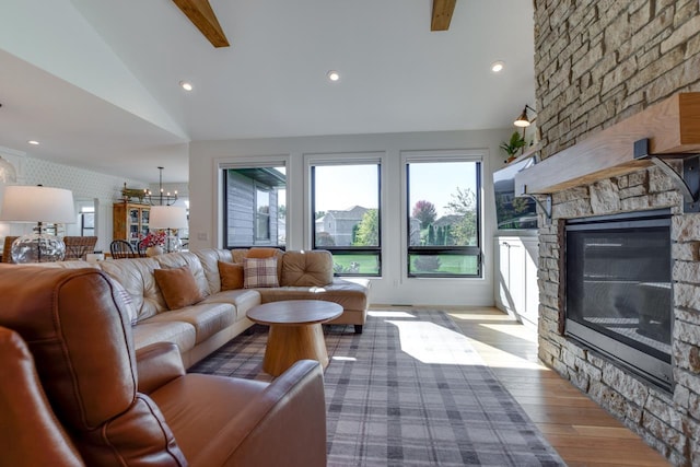 living room with a wealth of natural light, vaulted ceiling, a stone fireplace, and wood-type flooring