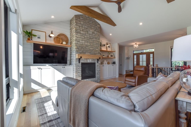 living room with ceiling fan, high vaulted ceiling, a fireplace, and light wood-type flooring