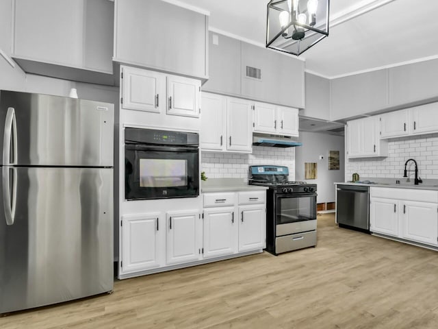 kitchen featuring pendant lighting, white cabinetry, sink, stainless steel appliances, and light wood-type flooring