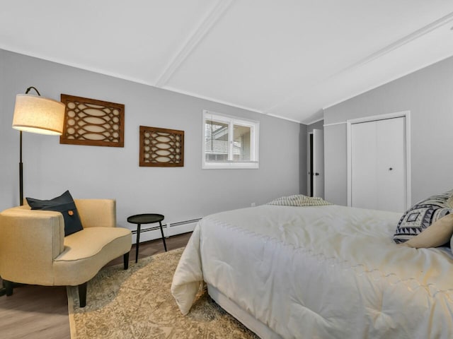 bedroom with wood-type flooring, lofted ceiling, a baseboard heating unit, and a closet