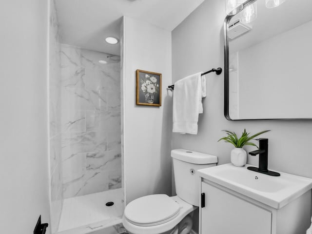 bathroom with vanity, tiled shower, and toilet