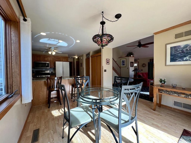 dining area with ornamental molding, ceiling fan, and light wood-type flooring