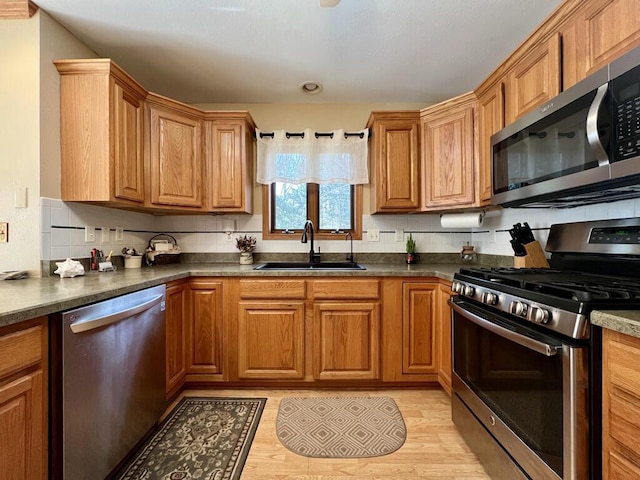 kitchen featuring stainless steel appliances, tasteful backsplash, sink, and light hardwood / wood-style flooring