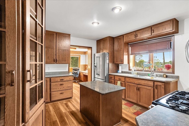 kitchen featuring sink, stainless steel appliances, a center island, and light wood-type flooring