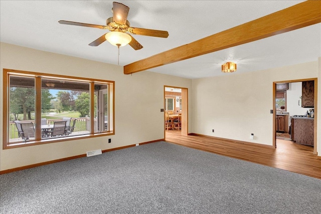 unfurnished living room with ceiling fan, carpet floors, and beam ceiling