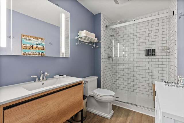 bathroom with a shower with door, vanity, wood-type flooring, and toilet