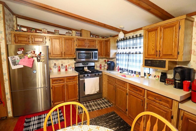 kitchen featuring stainless steel appliances, sink, hardwood / wood-style floors, and vaulted ceiling with beams