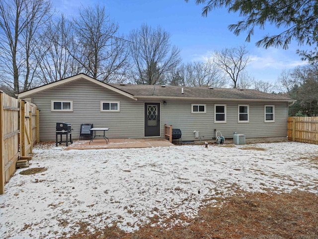 snow covered property with central AC unit and a patio area