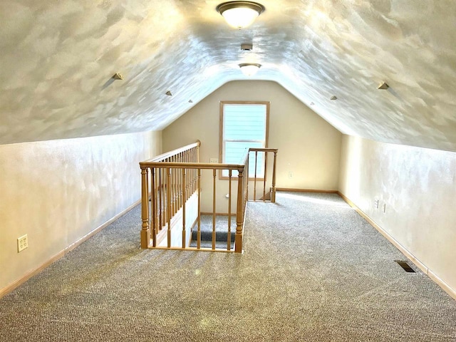 bonus room featuring vaulted ceiling, carpet, and a textured ceiling