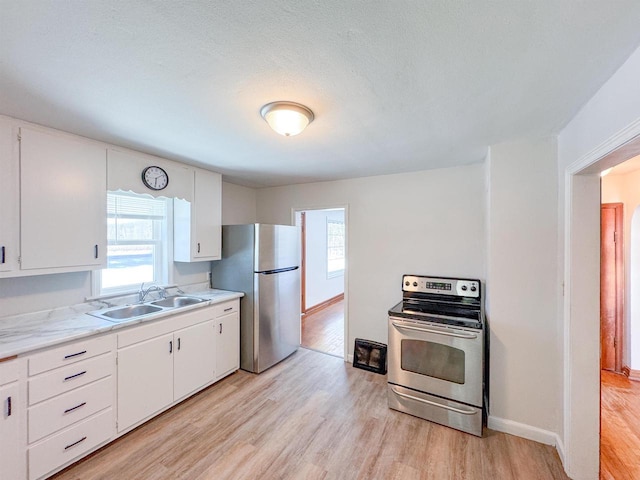 kitchen featuring light wood-type flooring, appliances with stainless steel finishes, sink, and white cabinets