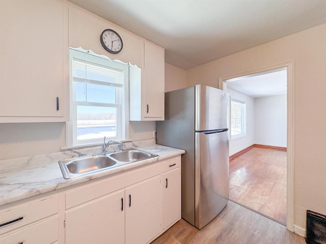 kitchen featuring white cabinetry, sink, stainless steel fridge, and light hardwood / wood-style flooring