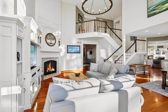 living room with dark hardwood / wood-style flooring, a stone fireplace, and a high ceiling