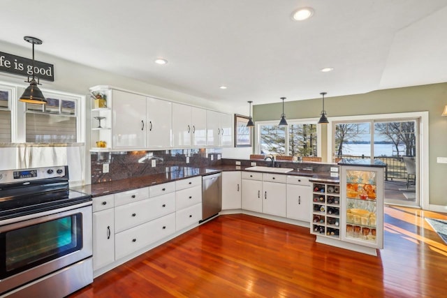 kitchen featuring dark wood-type flooring, sink, white cabinetry, appliances with stainless steel finishes, and pendant lighting