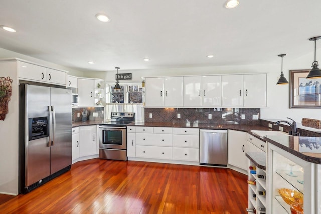 kitchen featuring hanging light fixtures, stainless steel appliances, and white cabinets