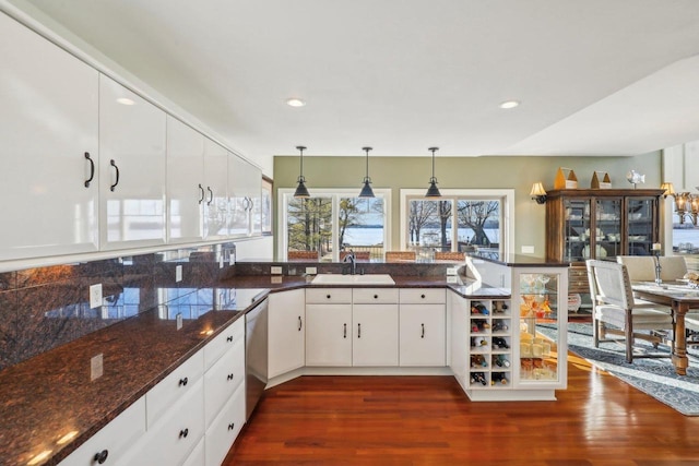 kitchen featuring white cabinetry, dark stone counters, kitchen peninsula, and sink