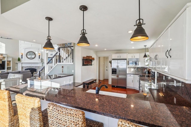 kitchen featuring appliances with stainless steel finishes, a breakfast bar, pendant lighting, white cabinetry, and sink