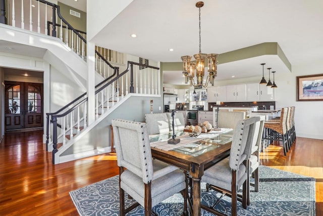 dining space with hardwood / wood-style flooring, a chandelier, and french doors