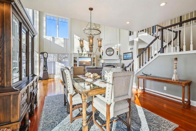 dining area with hardwood / wood-style flooring, a high ceiling, and an inviting chandelier