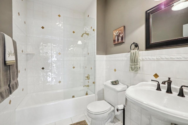 full bathroom with tile patterned floors, toilet, sink, tiled shower / bath, and tile walls