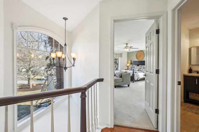 corridor featuring lofted ceiling, light colored carpet, and a notable chandelier