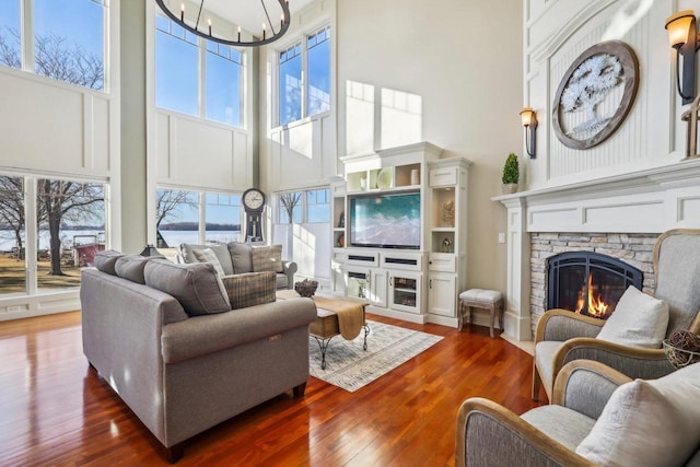 living room with an inviting chandelier, dark wood-type flooring, a fireplace, and a high ceiling