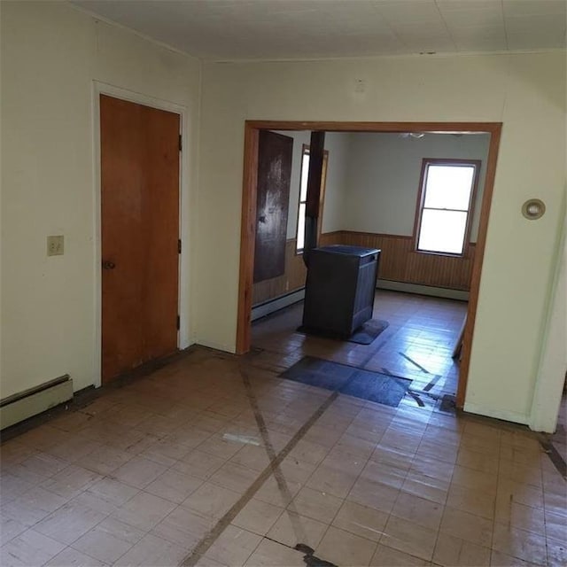 interior space with a baseboard heating unit and wood walls