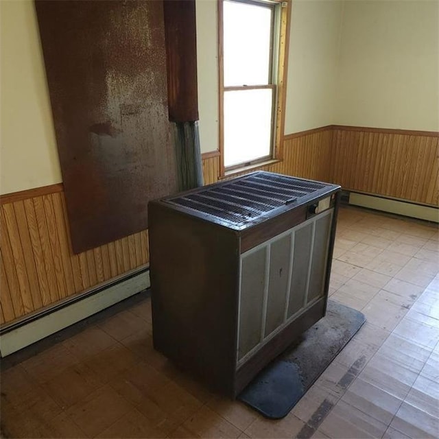 misc room with a baseboard radiator and wood walls