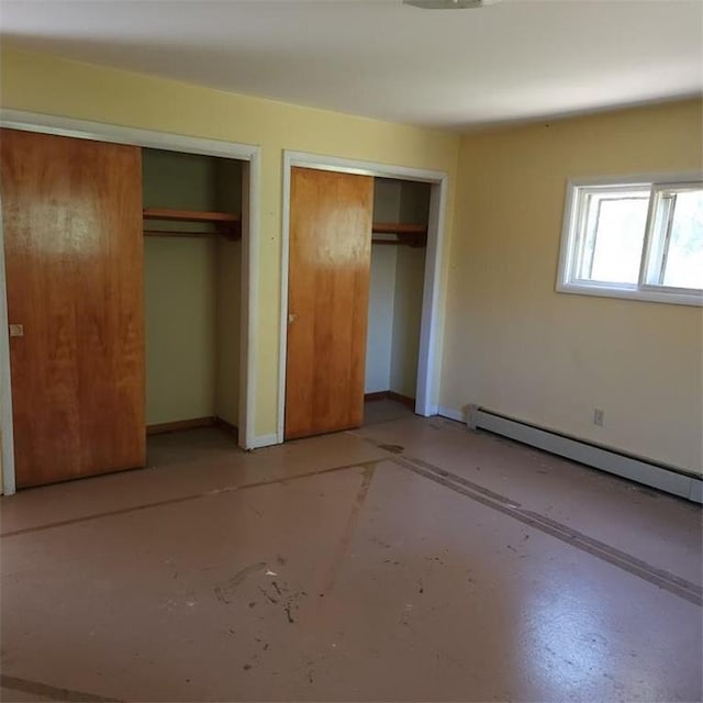 unfurnished bedroom with a baseboard radiator and two closets